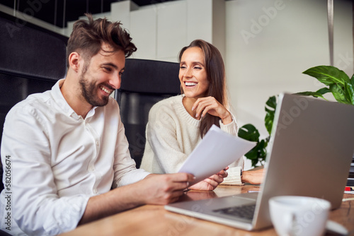 Two young business people having fun in office while working together