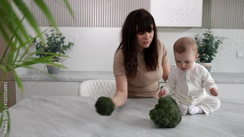 Mom feeds the baby broccoli. Healthy and natural baby food photo