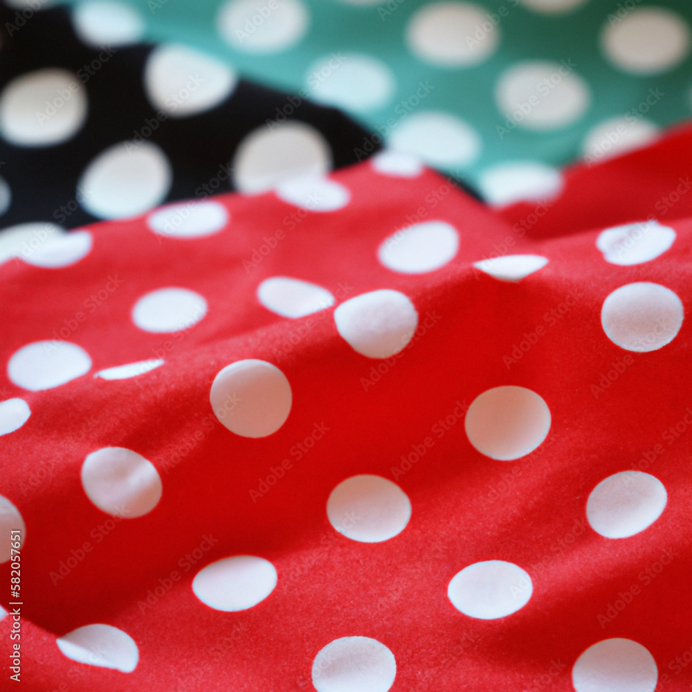 White polka dots on red pink background, textile fabric surface background. Green polka dot. Two layers of wrinkled material.