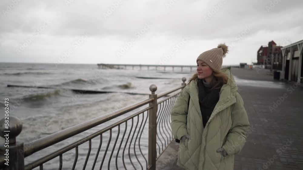A woman walks along the embankment near the sea in autumn A woman walks along the embankment near the sea in autumn