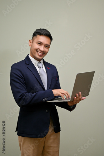 Successful Asian businessman in formal business suit holding his portable laptop, using laptop