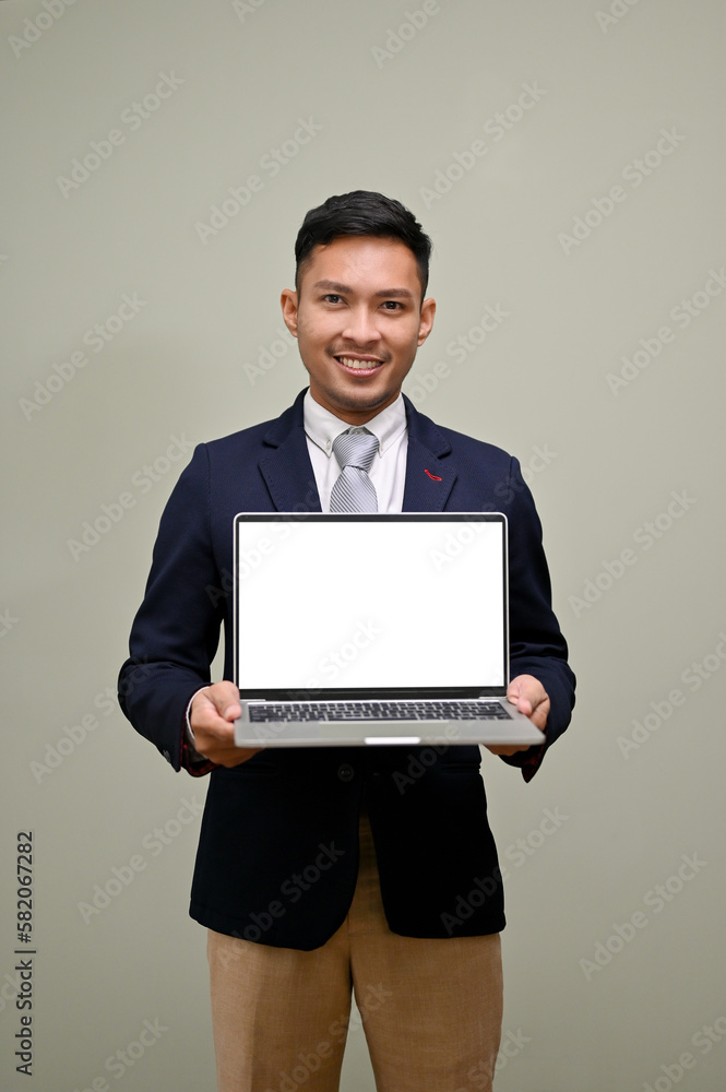 Handsome Asian businessman holding a laptop, showing laptop blank screen mockup