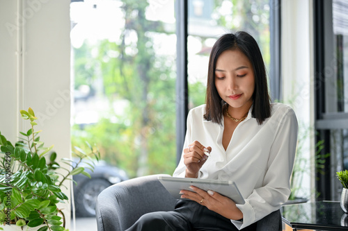 Charming Asian businesswoman using her tablet while relaxing in the coffee shop. Free Download Charming Asian businesswoman using her tablet while relaxing in the coffee shop. - GFXLoad
