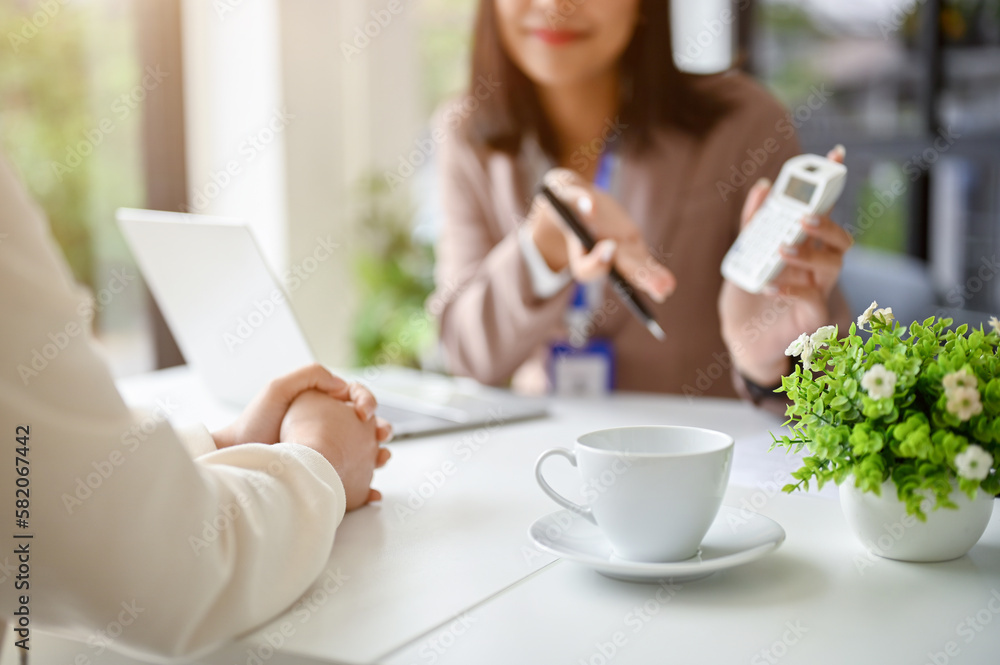 Cropped image of professional Asian female banker talking with a female client in the office. Cropped image of professional Asian female banker talking with a female client in the office.