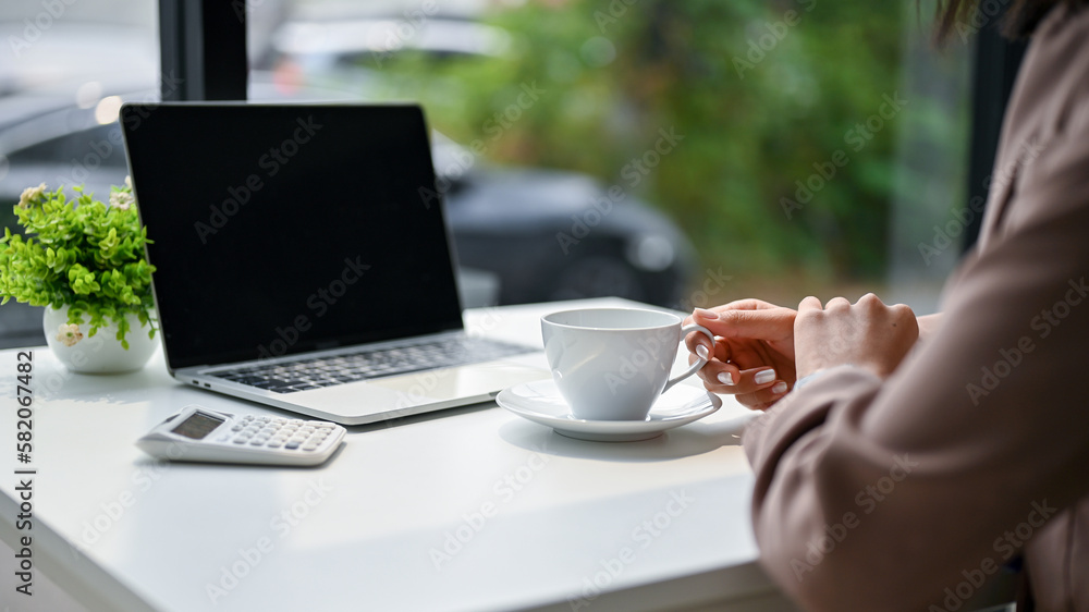 Close-up image of a businesswoman sipping coffee at her desk in the office. Close-up image of a businesswoman sipping coffee at her desk in the office.