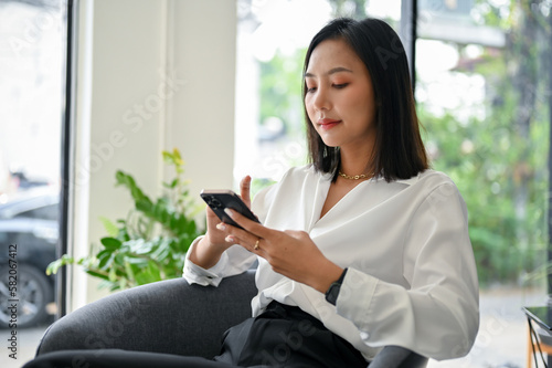 Gorgeous Asian businesswoman using her phone, chatting with someone or using mobile app Free Download Gorgeous Asian businesswoman using her phone, chatting with someone or using mobile app - GFXLoad