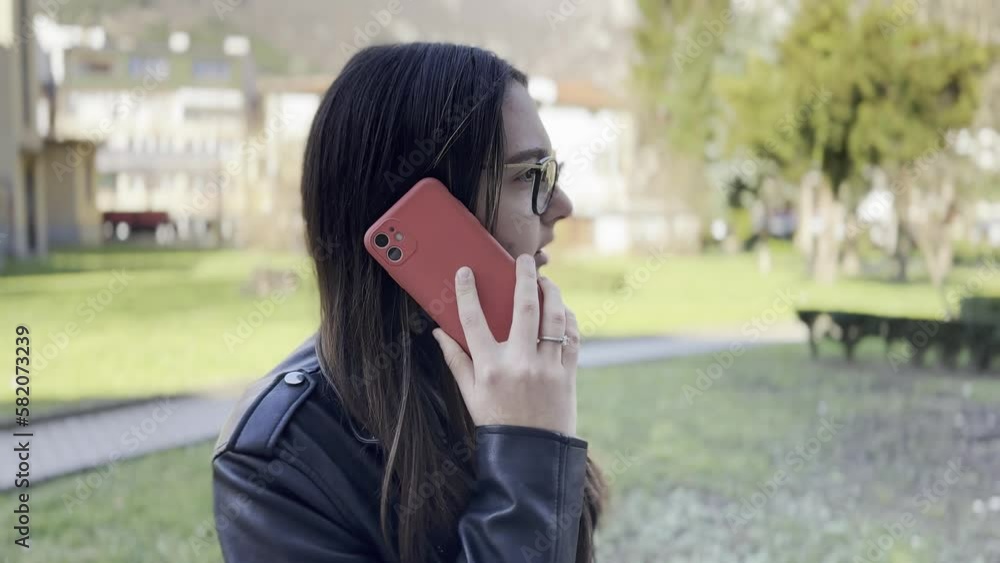 Woman talking on smartphone while standing in park Woman talking on smartphone while standing in park