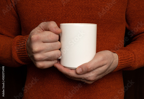 The man is holding a white cup. White cup without inscription.