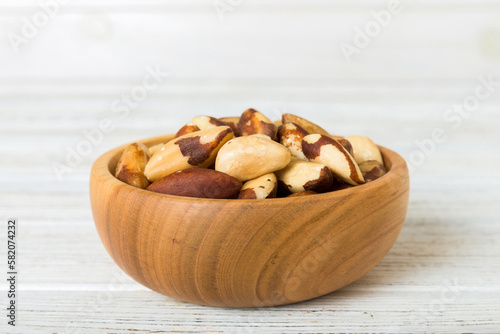 Fresh healthy Brazil nuts in bowl on colored table background. Top view Healthy eating bertholletia concept. Super foods