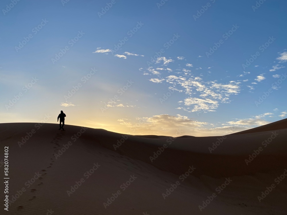 A silhouette of a man climbing a sand dune towards the sunrise 
Morocco 