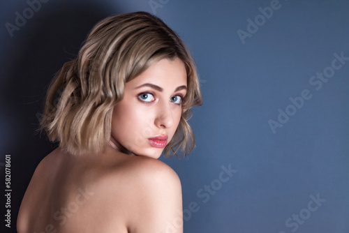 Close up portrait pensive young woman, posing at dark gray background, looking at camera. Emotional face of lovely blonde lady isolated on blank studio wall. Human emotions concept. Copy ad text space