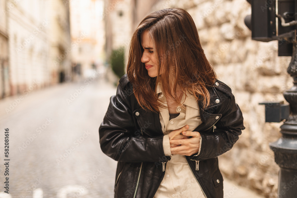 Woman standing outdoor with strong chest pain and hands touching her chest while having trouble at town, walking on the street. Heart attack or heart failure symptom Woman standing outdoor with strong chest pain and hands touching her chest while having trouble at town, walking on the street. Heart attack or heart failure symptom
