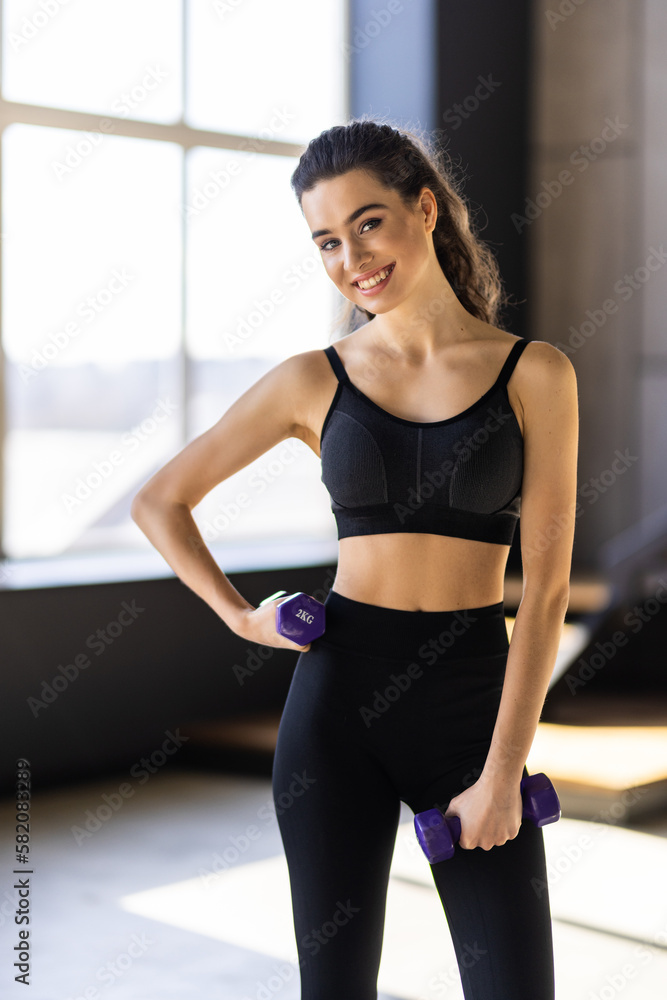 Sporty beautiful woman exercising with dumbbells at home to stay fit