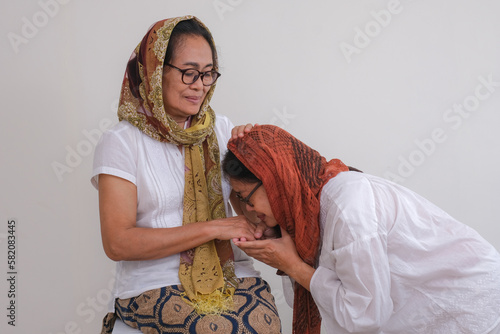 A woman is kissing her mother's hand as a sign of respect and apology photo