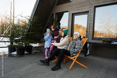 Mother with four children sit on terrace off grid tiny house in the mountains.