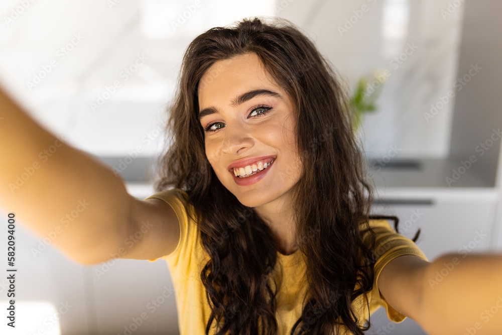 Cheerful young woman taking a selfie at the kitchen Cheerful young woman taking a selfie at the kitchen