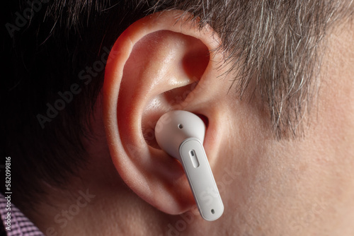 White wireless headphones in ear. Close up