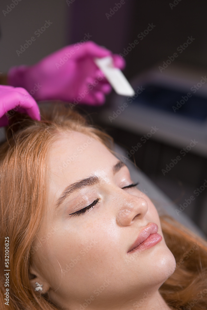 Fototapeta premium Beautician in a beauty salon examining the patient's hair before injecting medication. Mesotherapy for hair growth.