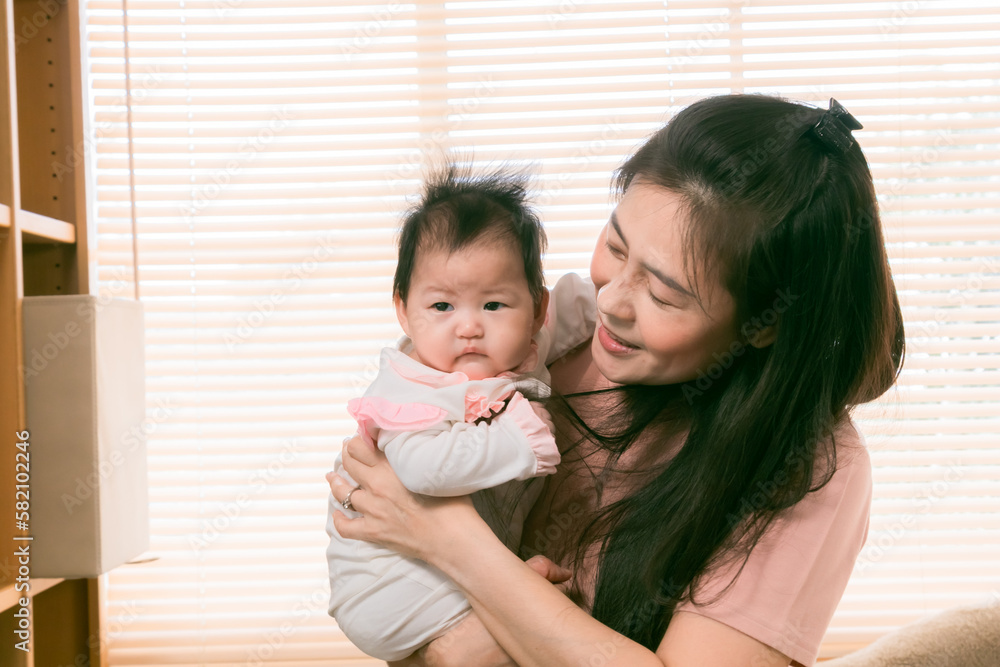 Asian beautiful mother holding adorable newborn baby with love and care, Happy affectionate mother spending time with adorable infant, motherhood lifestyle taking care taddler at home. Asian beautiful mother holding adorable newborn baby with love and care, Happy affectionate mother spending time with adorable infant, motherhood lifestyle taking care taddler at home.