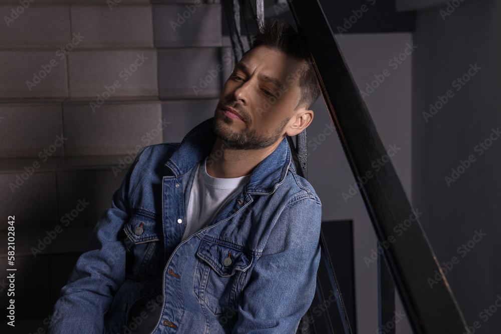 Upset man sitting on stairs indoors. Loneliness concept Upset man sitting on stairs indoors. Loneliness concept