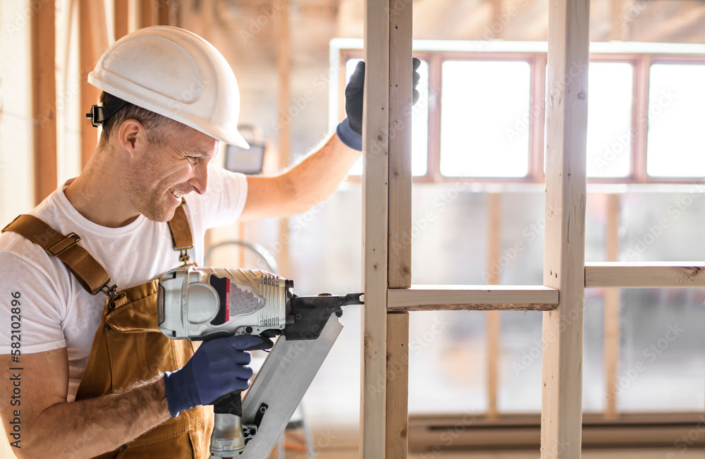 Worker using nail gun to build basement room Worker using nail gun to build basement room