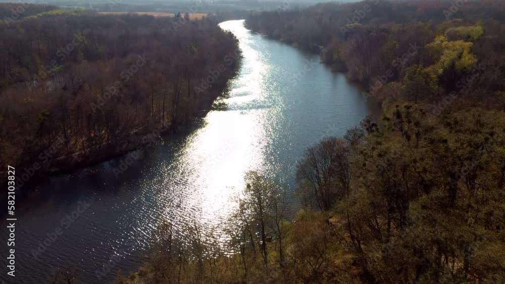 Panoramic natural view. River, sun glare on the surface of the water, trees on the banks on a sunny autumn day. Flying over water surface of river with sun glare. Aerial drone view. Nature landscape Panoramic natural view. River, sun glare on the surface of the water, trees on the banks on a sunny autumn day. Flying over water surface of river with sun glare. Aerial drone view. Nature landscape