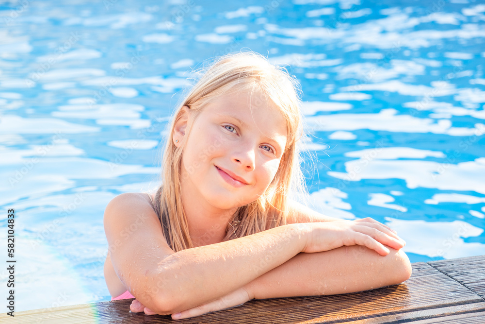 Blonde little girl smiling in a pool. Vacation and holiday concept.