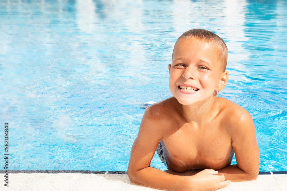 Happy smiling boy in a pool. Summer vacation concept. Text space