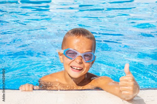 Smiling boy in a in a pool. Boy with swimming goggles. Summer vacation concept. Childhood
