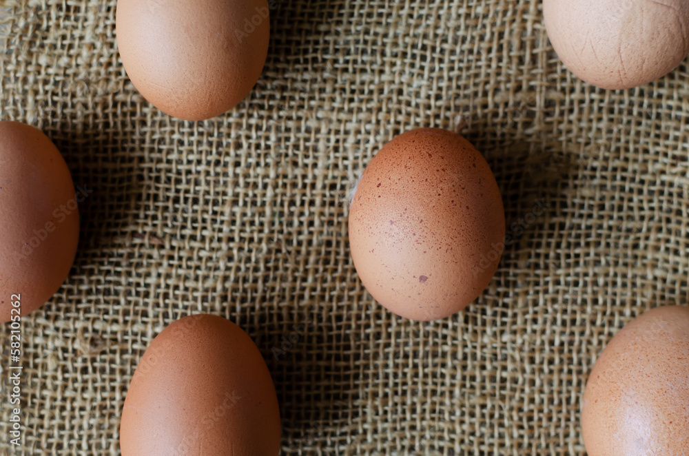 A lot of chicken eggs on burlap on a wooden background. Rustic style. The concept of organic food. Horizontal orientation. Top view. A lot of chicken eggs on burlap on a wooden background. Rustic style. The concept of organic food. Horizontal orientation. Top view.