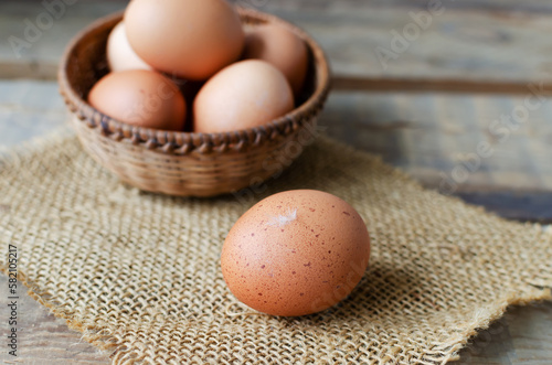 Chicken eggs in a wicker bowl on burlap on a wooden background. Rustic style. The concept of organic food. Selective focus. Horizontal orientation.