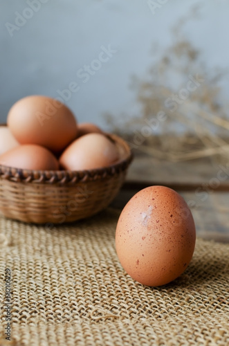 Chicken eggs in a wicker bowl on burlap on a wooden background. Rustic style. The concept of organic food. Selective focus. Vertical orientation.