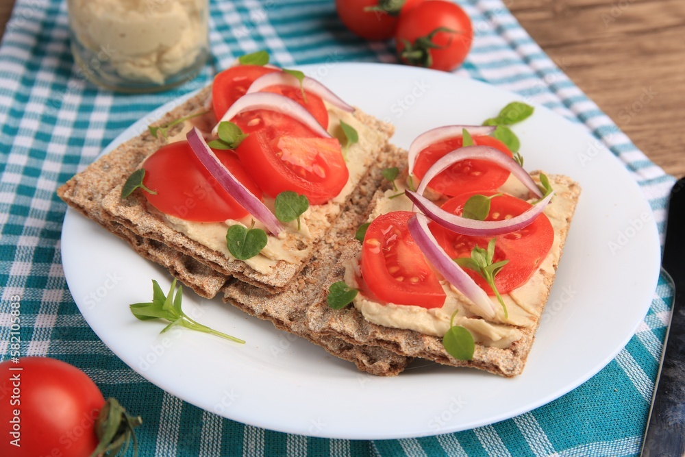 Fresh crunchy crispbreads with pate, tomatoes, red onion and greens on table