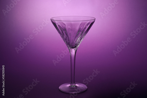 Elegant empty martini glass on purple background