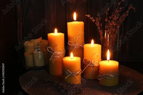 Beautiful burning beeswax candles and dried lavender flowers on table