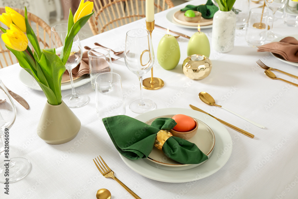 Festive Easter table setting with painted eggs, burning candles and yellow tulips - obrazy, fototapety, plakaty 