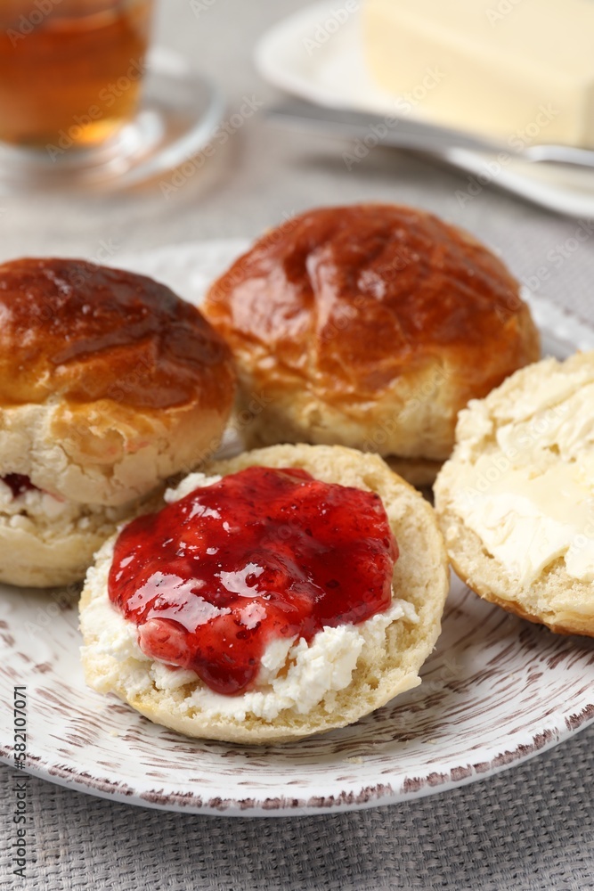 Freshly baked soda water scones with cranberry jam and butter on light grey mat, closeup Freshly baked soda water scones with cranberry jam and butter on light grey mat, closeup