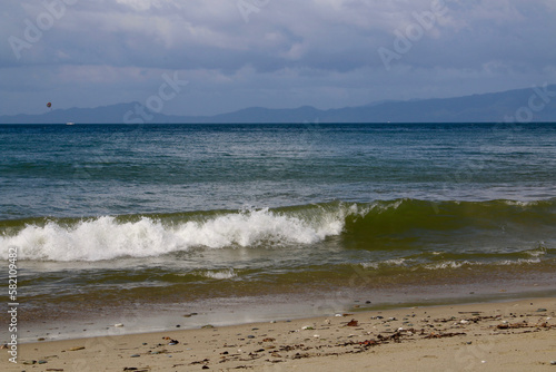 Sandy beach of a tropical island. Overcast weather. Sea wave rolls on the sandy beach.