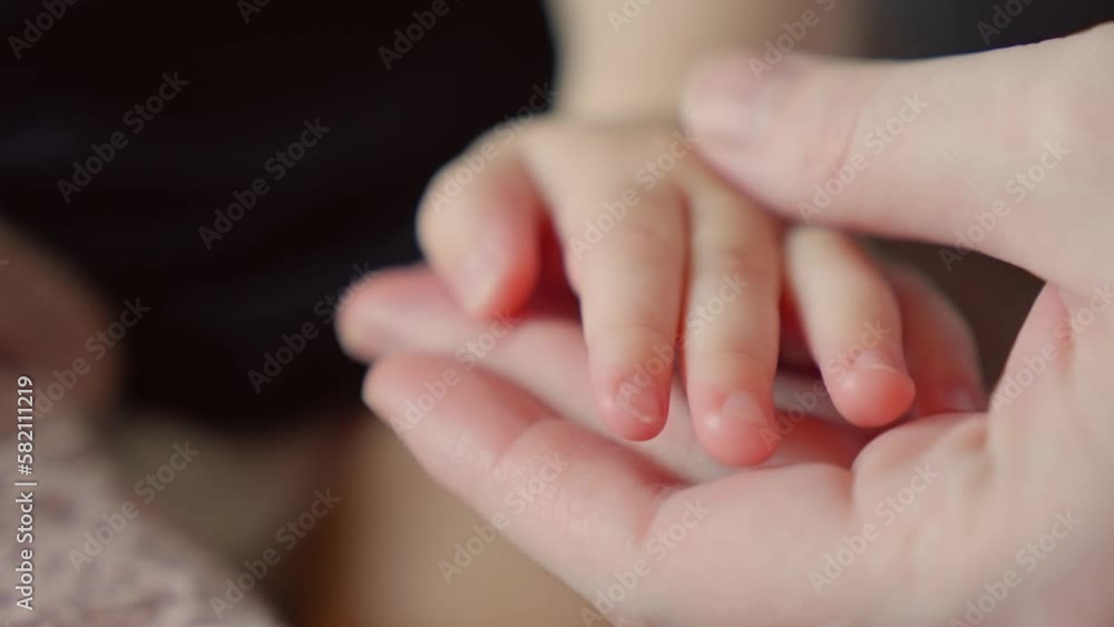 mother holds the hand of a newborn. children hand. hospital takes care of happy family medicine concept. newborn baby holding mom hand close-up. close-up mom takes care baby in the hospital