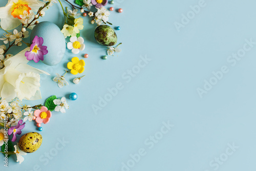 Canvas Print Stylish easter eggs, candy and blooming flowers on blue background flat lay