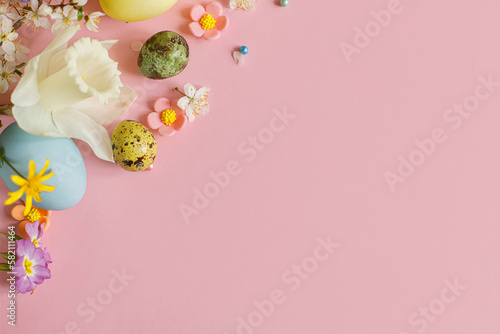 Stylish easter eggs, candy and blooming flowers on pink background flat lay. Happy Easter! Natural painted colorful eggs and spring blossom. Modern greeting card or banner, copy space