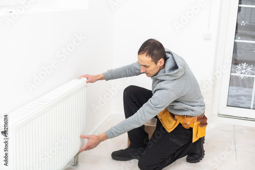 repairman using tools while installing or repairing heating radiator. plumber installing heating system in apartment. radiator installation, plumbing works and home renovation