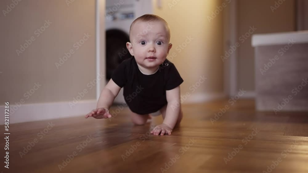 baby learns to crawl on the floor at home. happy family kindergarten kids concept. First steps, baby crawling front view . baby learns to crawl to explore the world around dream him baby learns to crawl on the floor at home. happy family kindergarten kids concept. First steps, baby crawling front view . baby learns to crawl to explore the world around dream him