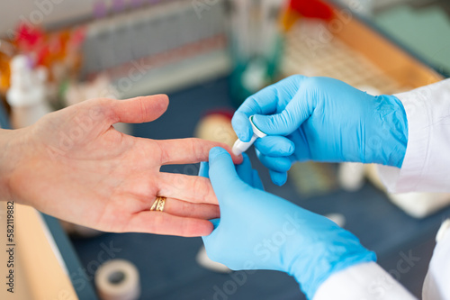 The doctor measures the patient's C-reactive protein (CRP). The doctor draws blood from the patient's finger.