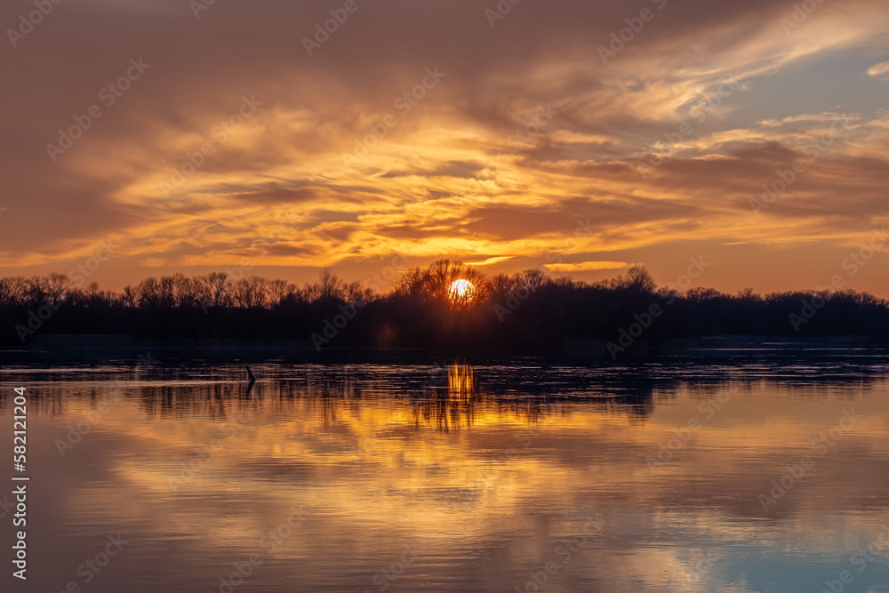 Picturesque sunset with reflection of clouds and trees on the water surface of the wide Dnieper river. HDR photo