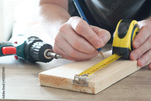 Carpenter hand measuring tape with pen in construction site. Making measurements with measuring tape and making marks with pen.