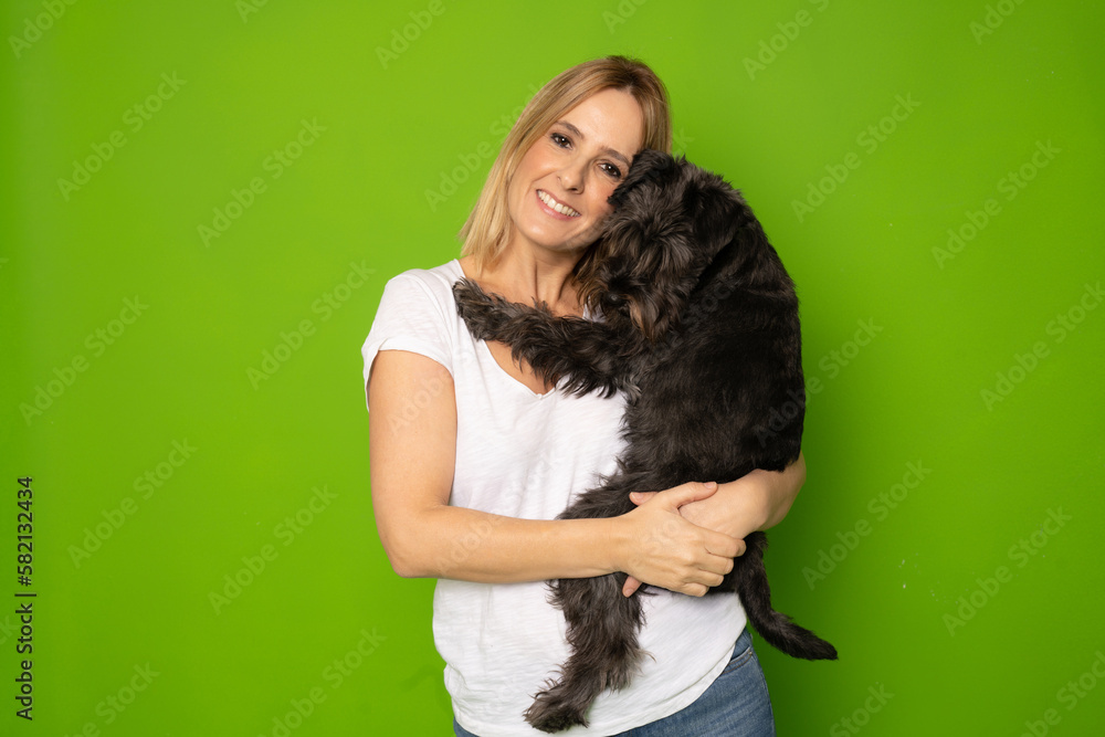 Portrait of attractive cheerful careful girl holding in hands doggy schnauzer isolated over bright green color background