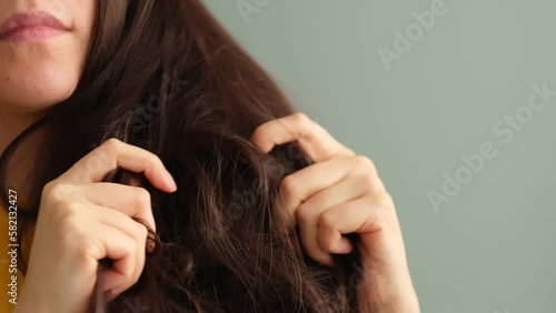 common problem of dry, tangled hair with this video of a distressed brunette woman examining her locks. hair treatments, conditioners, and products designed to restore hair's health and manageability.