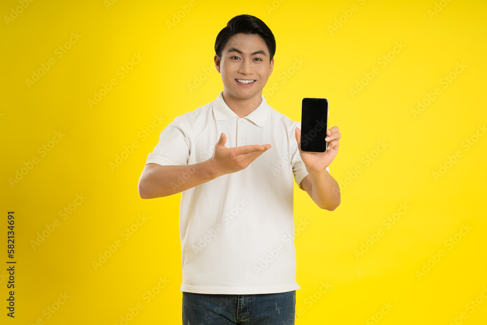 Portrait of young asianman using phone on yellow background Portrait of young asianman using phone on yellow background