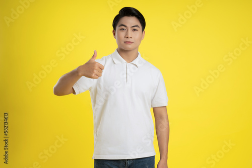 Portrait of young asian man posing on yellow background